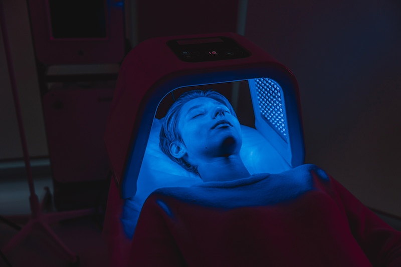 A woman is lying down and receiving Celluma LED light therapy treatment in addition to laser resurfacing in Oklahoma City.