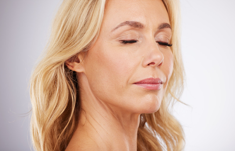 A woman is soft smiling and is showing the results from her buccal fat removal in Jacksonville.