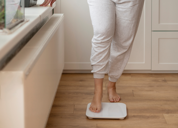 A woman is standing on the scale after visiting Cosmetic Surgery Affiliates for weight loss injections and a fat transfer, which a method for how to lose belly fat in Jacksonville.