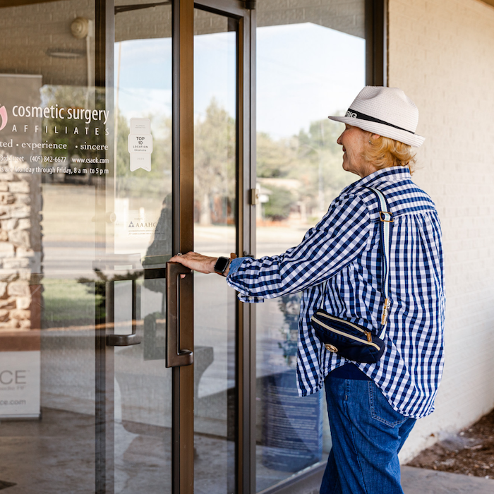 A woman is walking into Cosmetic Surgery Affiliates to learn how to lose belly fat in OKC.