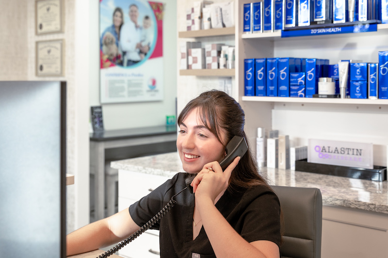 A woman at the front desk of Cosmetic Surgery Affiliates weight loss clinic in Jacksonville is helping a patient check in.