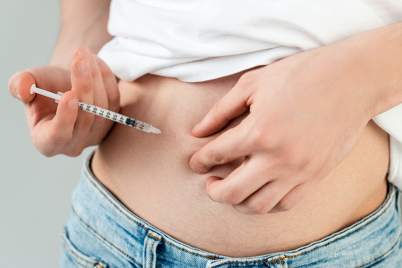 A woman is injecting semaglutide into her abdomen as one method for how to lose belly fat in Jacksonville.